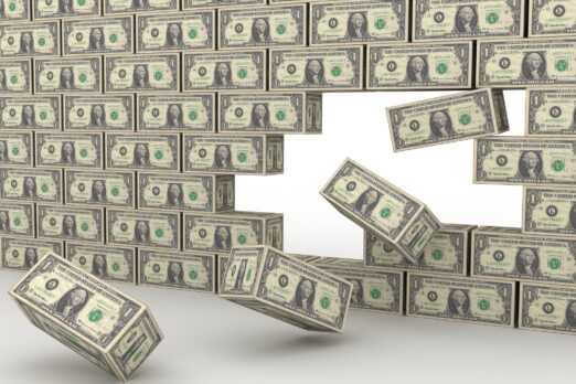 A 3D image of a wall made of US one-dollar bills, with several blocks falling from the right side, suggesting construction.