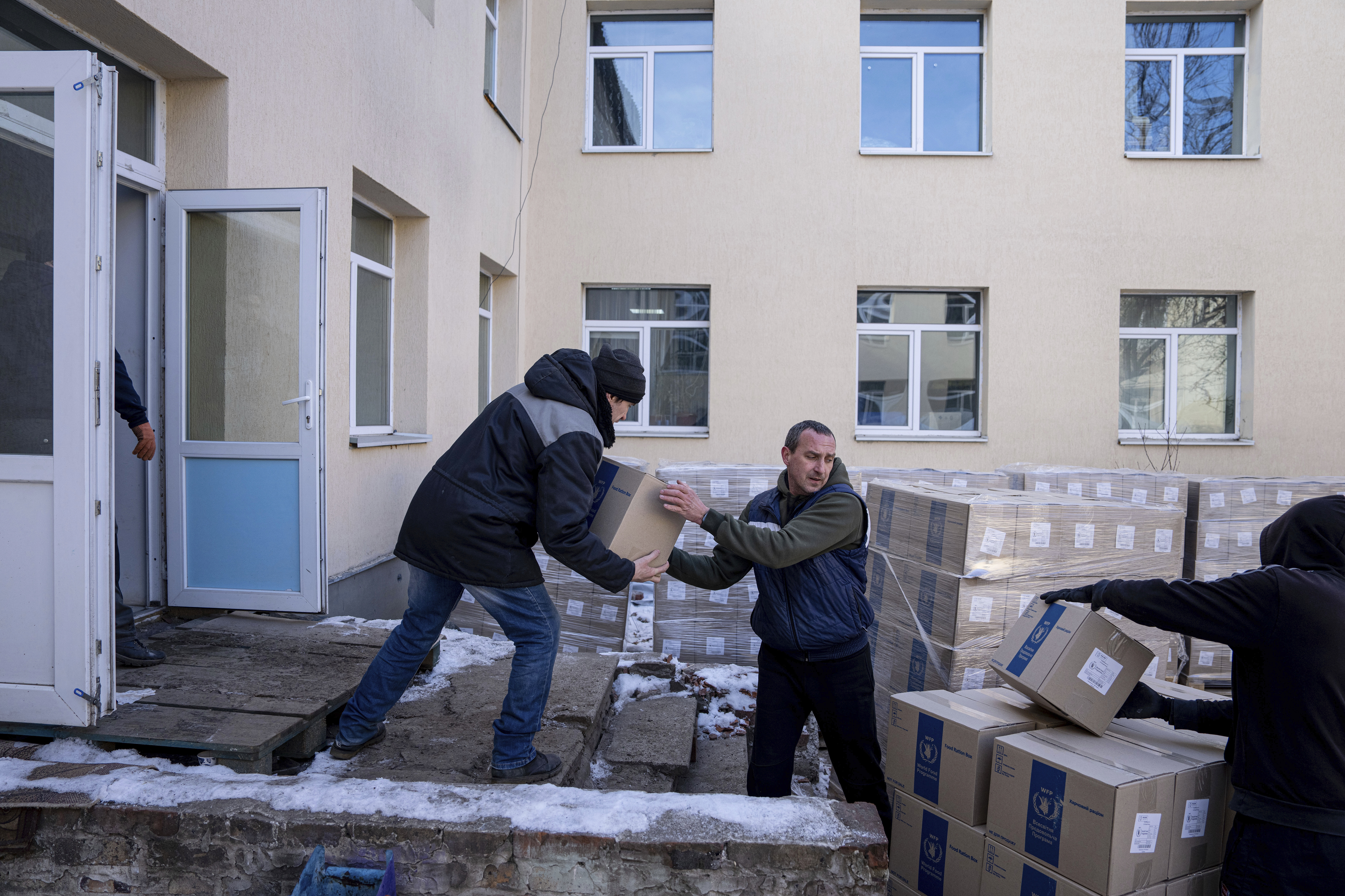 Men unload boxes with humanitarian aid provided by UN World Food Program and ADRA charity organisation for the residents of the region and internally displaced persons at the distribution center in Kostiantynivka, Ukraine, Friday, Feb. 10, 2023.