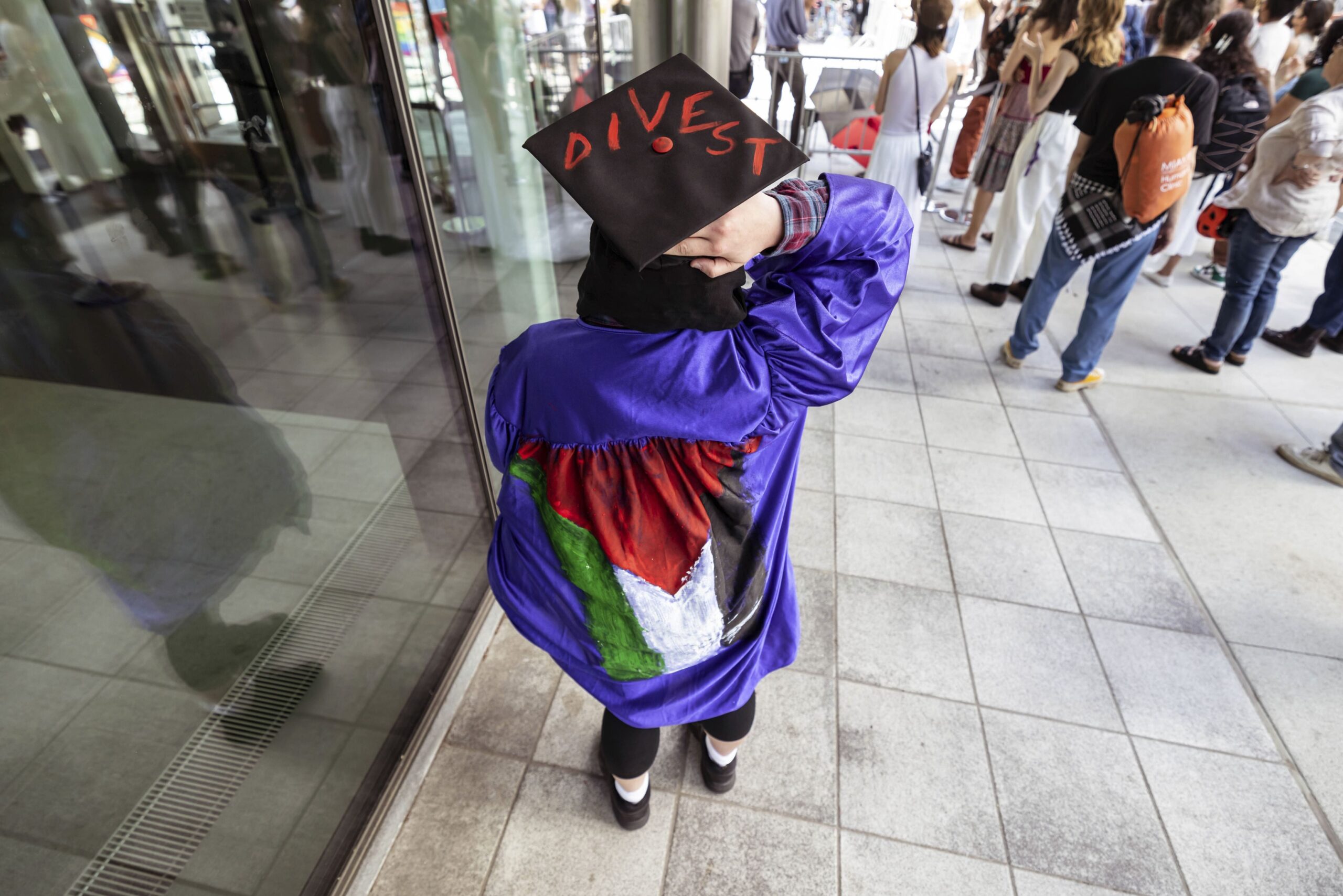 A student at New York University wears a graduation cap and gown marked with messages of solidarity with Palestine, at a student encampment at NYU on April 26, 2024 in New York City.