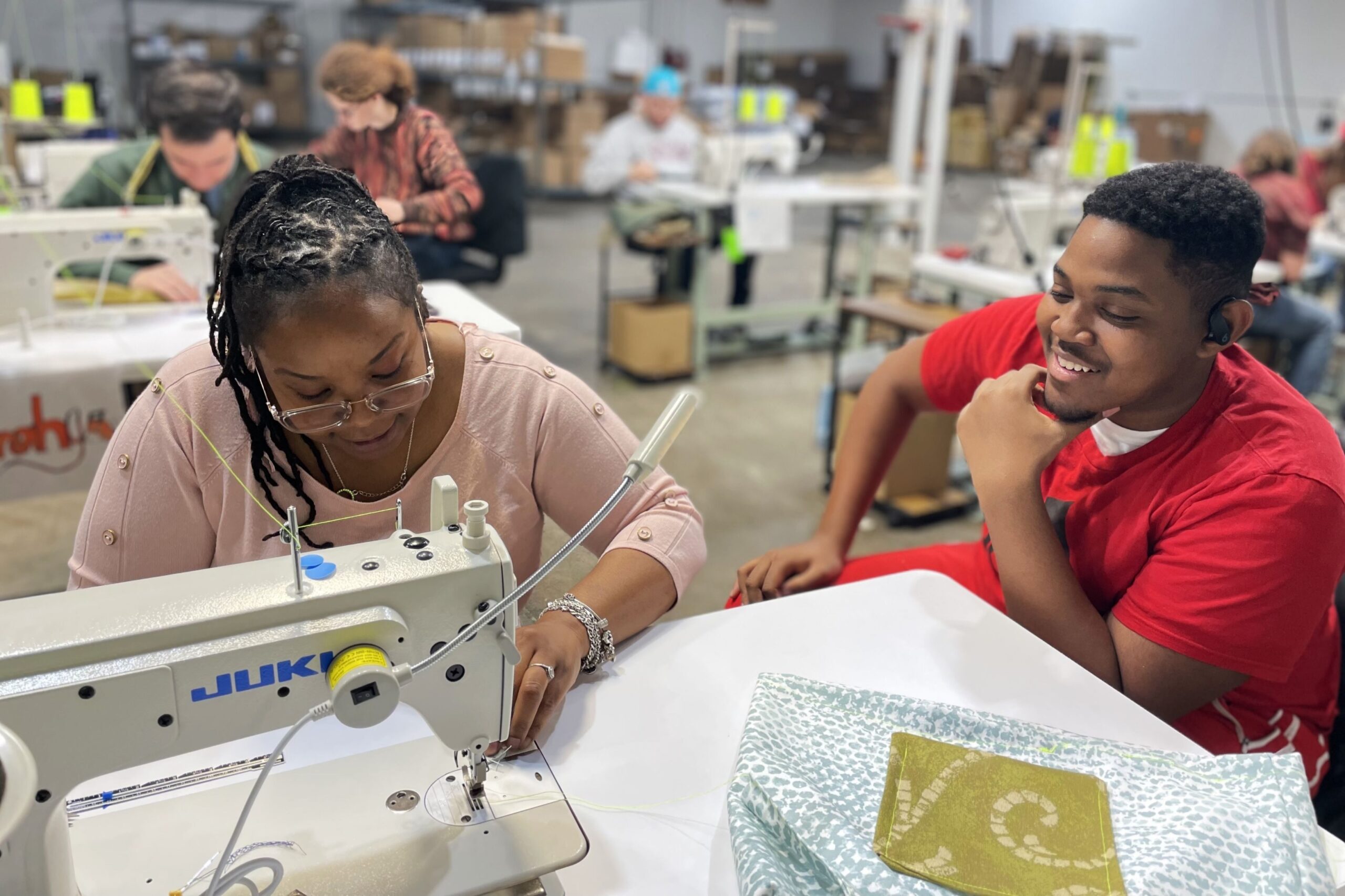 A Fordham Univeristy student sits with Ashley to learn about textile work in a program focused on sustainable circular economic models organized through the Industrial Commons.