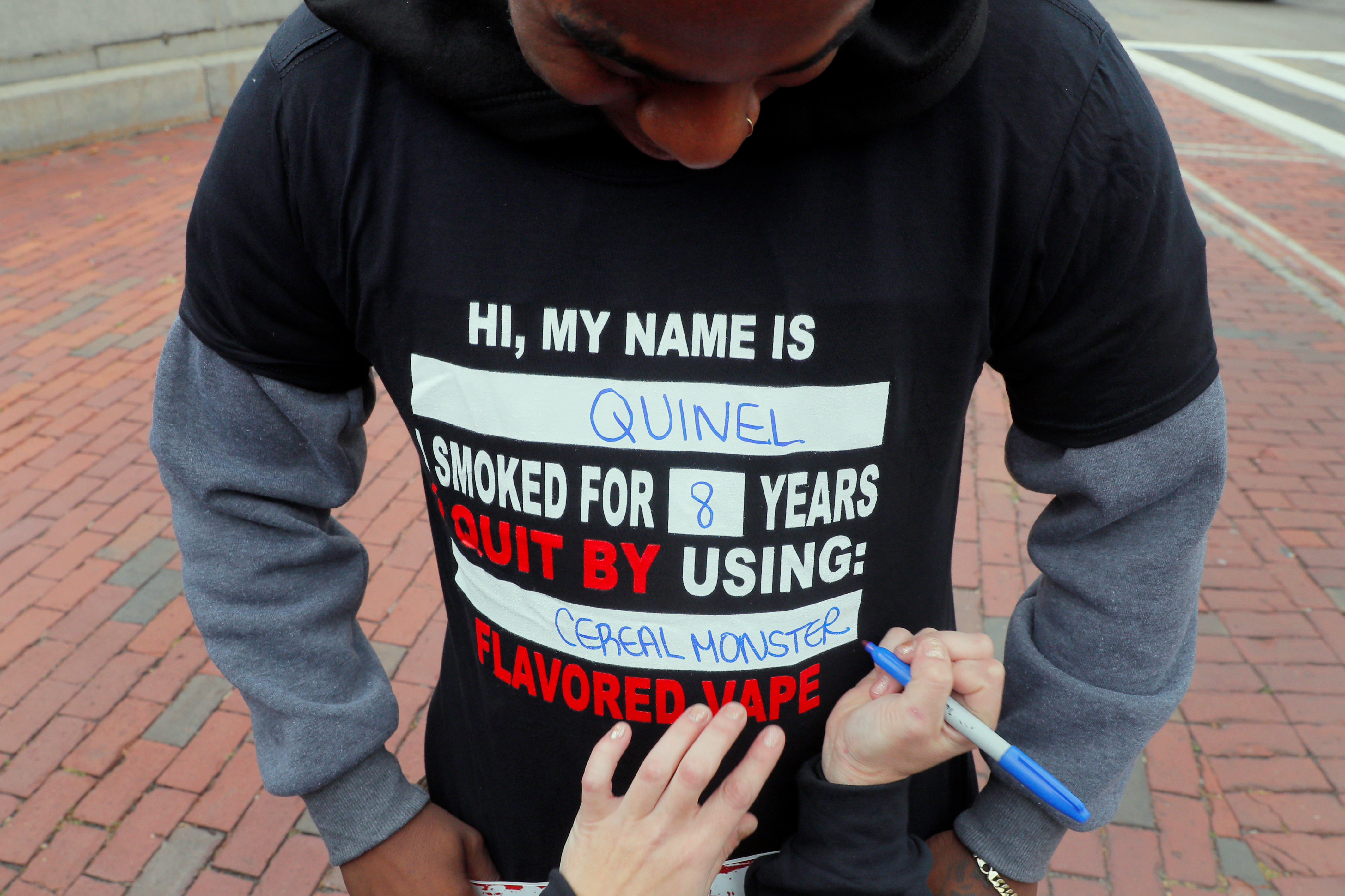 Demonstrators wear t-shirts displaying how they quit smoking by using flavored vape during a protest at the Massachusetts State House against the state’s four-month ban of all vaping product sales in Boston, Massachusetts, U.S., October 3, 2019.