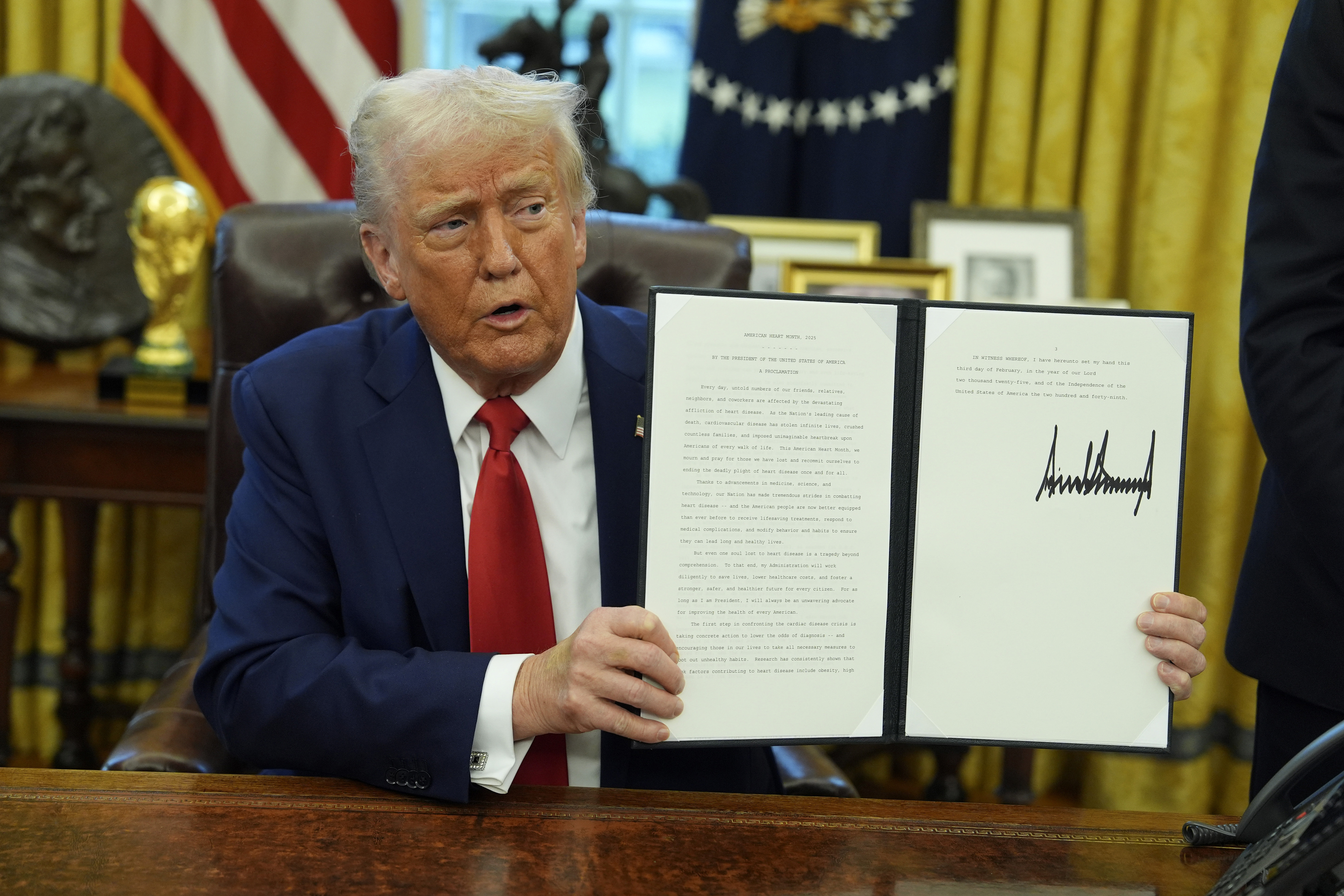 President Donald Trump holds up a signed executive order in the Oval Office of the White House, Monday, Feb. 3, 2025, in Washington.