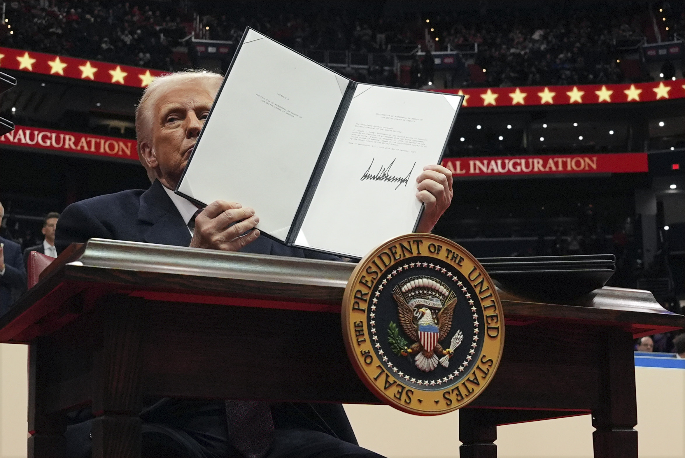 President Donald Trump signs an executive order as he attends an indoor Presidential Inauguration parade event at Capital One Arena, Monday, Jan. 20, 2025, in Washington.
