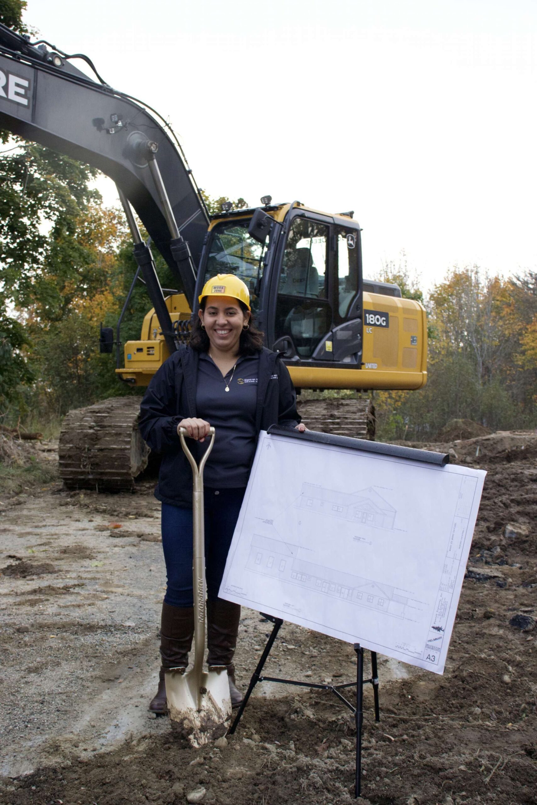 Juana Rodriguez Vazquez stands wearing a hard hat and holding a shovel