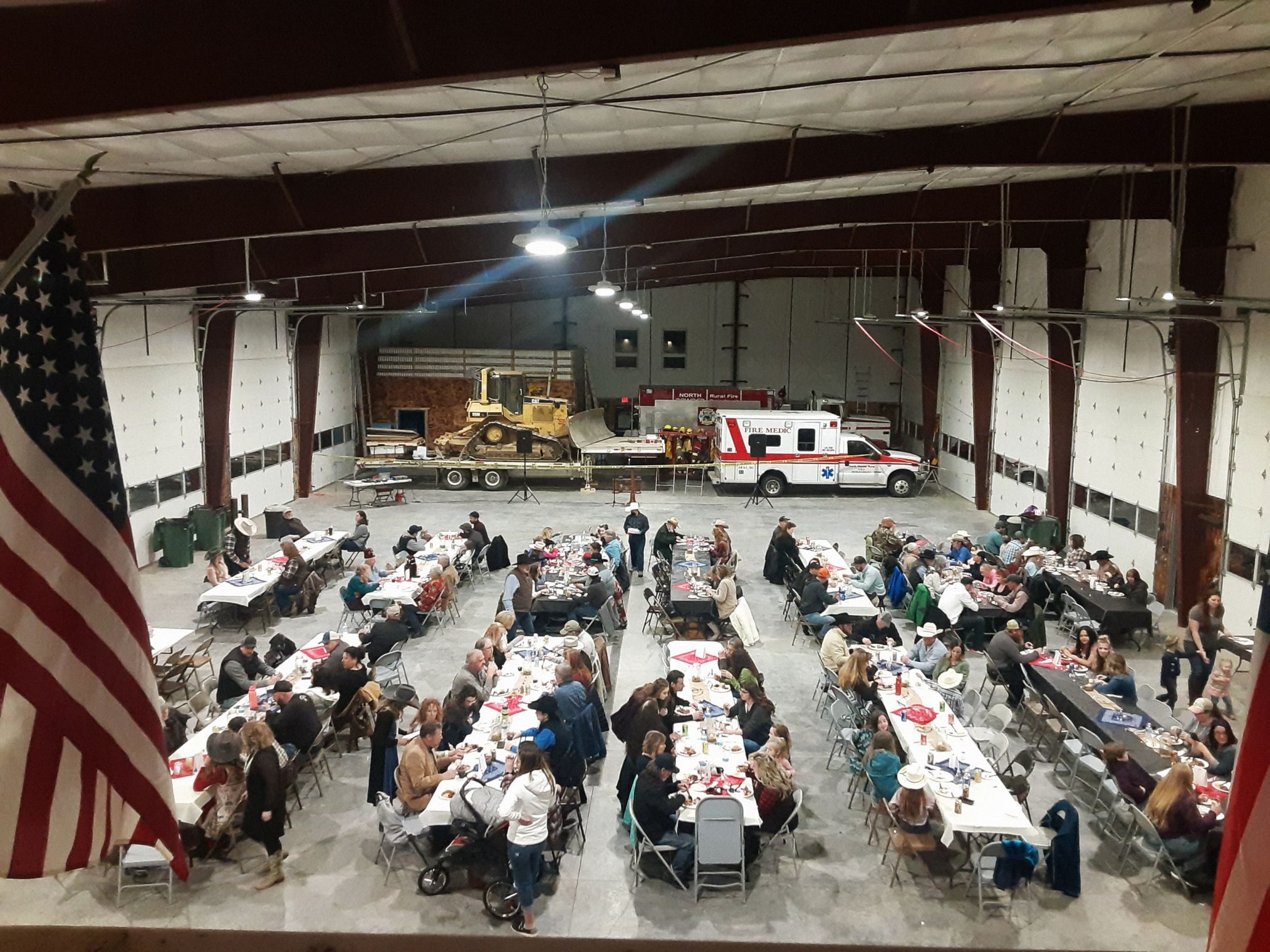 People sit at tables set up in a large room. 