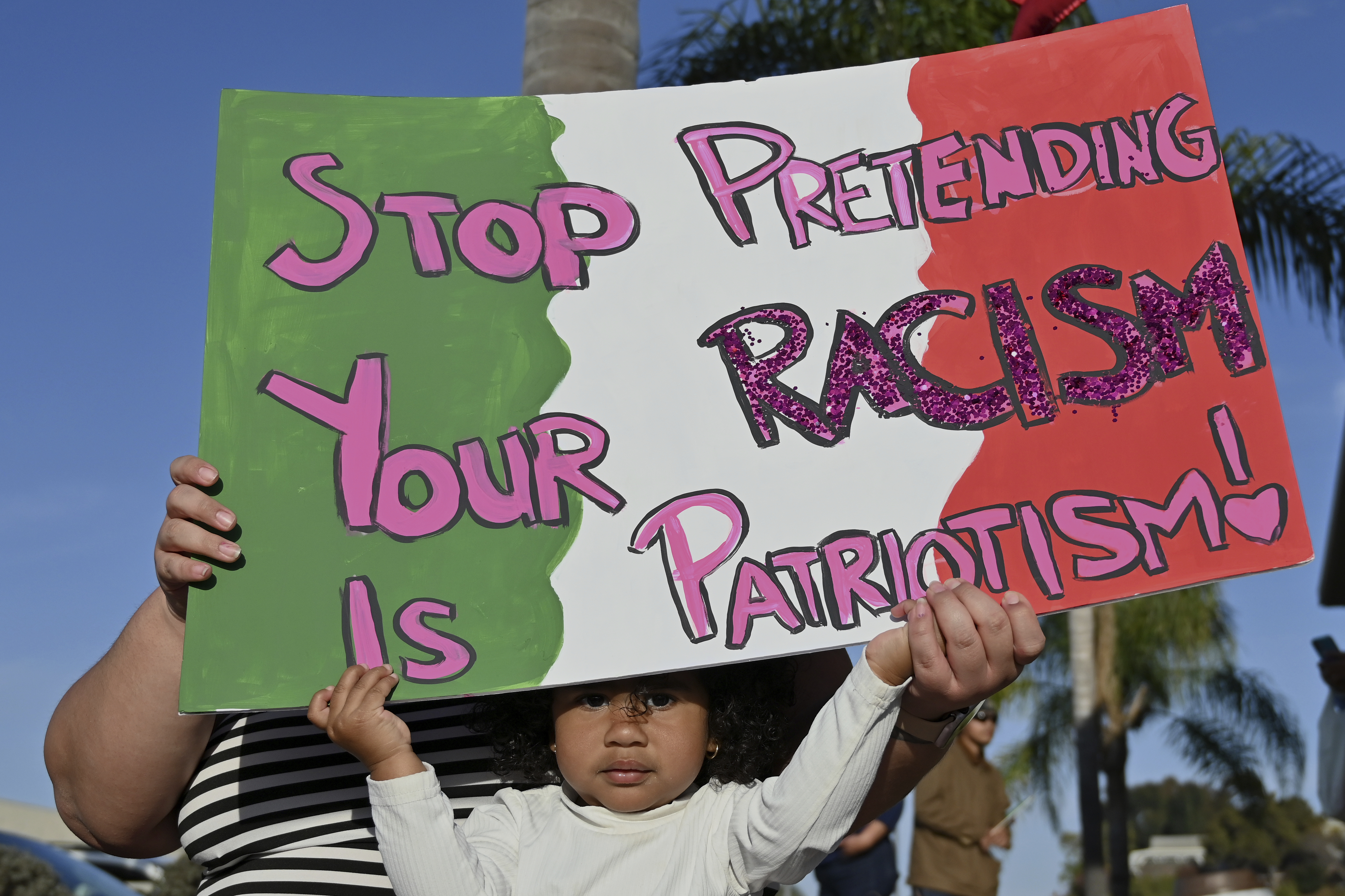 A child and her mom hoist a sign as they gather with protesters demonstrating against anti-immigrant policies towards Mexicans living and working in the U.S. and San Diego, in National City, San Diego County, on January 31, 2025.