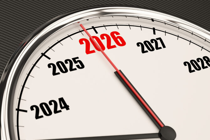 A clock face with a red hand pointing to the year 2026, which is highlighted in red. Other years like 2024, 2025, 2027, 2028 are also visible on the white dial, encased in a chrome bezel against a dark textured background.