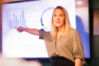 A woman standing in front of a presentation about gathering data to show impact